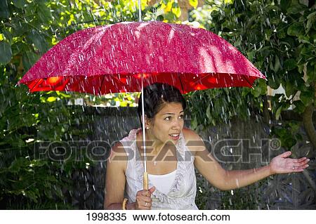 Stock Photography - A Woman In The Rain Under An Umbrella; Delta British Columbia Canada. Fotosearch