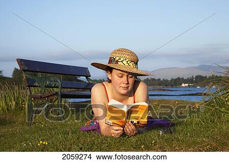 A Woman Reads A Book By The Water's Edge; County Kerry Ireland View Large Photo Image Picture - A Woman Reads A Book By The Water's Edge; County Kerry Ireland. Fotosearch