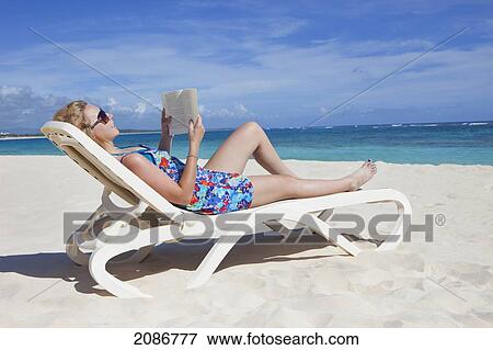 A woman reads a book on a beach chair by the ocean; punta cana la altagracia dominican republic View Large Photo Image Stock Photo - A woman reads a book on a beach chair by the ocean; punta cana la altagracia dominican republic. Fotosearch