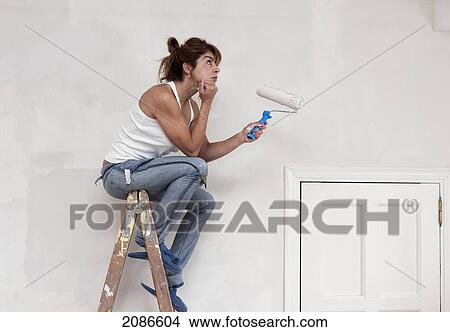 A woman sits at the top of a ladder with a paint roller in her hand; tarifa cadiz andalusia spain View Large Photo Image Picture - A woman sits at the top of a ladder with a paint roller in her hand; tarifa cadiz andalusia spain. Fotosearch