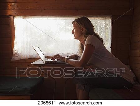 A Woman Sits Beside A Window Working On Her Computer; Tarifa Cadiz Andalusia Spain View Large Photo Image Stock Image - A Woman Sits Beside A Window Working On Her Computer; Tarifa Cadiz Andalusia Spain. Fotosearch