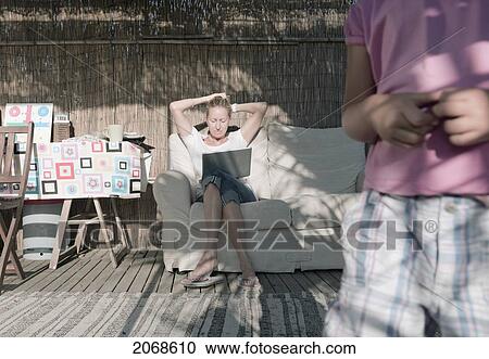 A Woman Sits On A Couch With Her Son In The Foreground; Tarifa Cadiz Andalusia Spain View Large Photo Image Stock Image - A Woman Sits On A Couch With Her Son In The Foreground; Tarifa Cadiz Andalusia Spain. Fotosearch