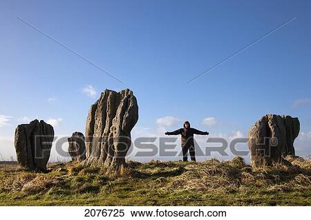 Stock Photography - A woman standing beside the standing stones of duddo; northumberland england. Fotosearch
