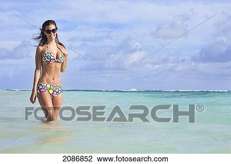 A woman standing in the ocean wearing a colourful bikini and sunglasses; punta cana la altagracia dominican republic View Large Photo Image Stock Image - A woman standing in the ocean wearing a colourful bikini and sunglasses; punta cana la altagracia dominican republic. Fotosearch