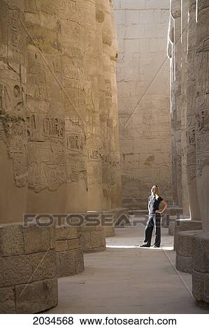 Stock Photo - A Woman Tourist Stands At The Base Of The Massive Columns In The Temples Of Karnak On The East Bank Of Luxor Along The Nile River; Luxor Egypt. Fotosearch
