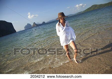 Stock Image - A Woman Tourist Walks In Shallow Clear Water On A Sand Island Near El Nido And Corong Corong; Bacuit Archipelago Palawan Philippines. Fotosearch