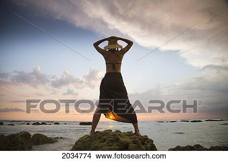 A Woman Tourist Wearing A Hat And Sarong Stands On The Beach Of A Tropical Island At Sunset; Koh Lanta Thailand View Large Photo Image Picture - A Woman Tourist Wearing A Hat And Sarong Stands On The Beach Of A Tropical Island At Sunset; Koh Lanta Thailand. Fotosearch