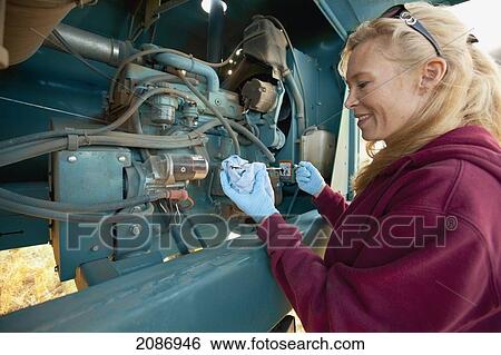 Stock Photograph - A woman working on heavy equipment on a farm; three hills alberta canada. Fotosearch