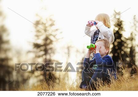 A young boy and girl looking through binoculars; spruce grove alberta canada View Large Photo Image Stock Photograph - A young boy and girl looking through binoculars; spruce grove alberta canada. Fotosearch