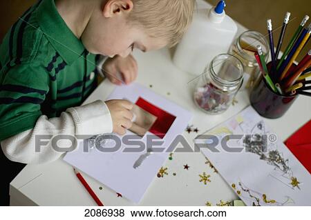 Stock Photo - A young boy making christmas cards; cambridge united kingdom. Fotosearch