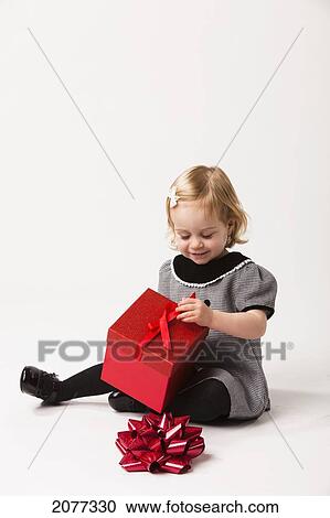 A young girl sits opening a red gift box against a white background; nashville tennessee united states of america View Large Photo Image Stock Image - A young girl sits opening a red gift box against a white background; nashville tennessee united states of america. Fotosearch