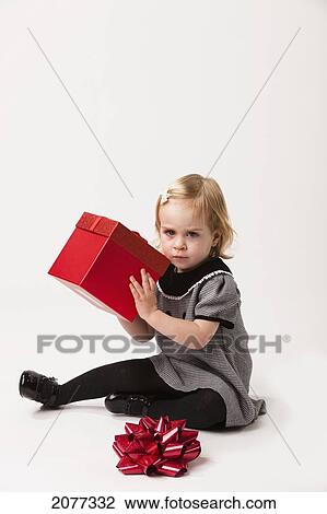 A young girl sits opening a red gift box against a white background; nashville tennessee united states of america View Large Photo Image Stock Image - A young girl sits opening a red gift box against a white background; nashville tennessee united states of america. Fotosearch