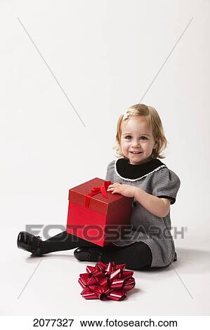 A young girl sits opening a red gift box against a white background; nashville tennessee united states of america View Large Photo Image Stock Photo - A young girl sits opening a red gift box against a white background; nashville tennessee united states of america. Fotosearch