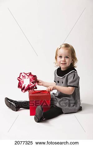 A young girl sits opening a red gift box against a white background; nashville tennessee united states of america View Large Photo Image Stock Photography - A young girl sits opening a red gift box against a white background; nashville tennessee united states of america. Fotosearch