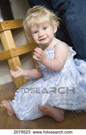 A young girl with blond hair and blue eyes sitting on the floor in a dress; millet alberta canada View Large Photo Image Stock Image - A young girl with blond hair and blue eyes sitting on the floor in a dress; millet alberta canada. Fotosearch