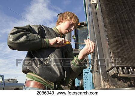 A young man repairs farm equipment; three hills alberta canada View Large Photo Image Stock Photo - A young man repairs farm equipment; three hills alberta canada. Fotosearch
