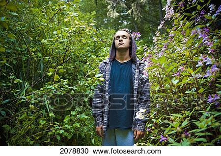 Stock Image - A young man stands calmly in a forest with eyes closed; tofino british columbia canada. Fotosearch