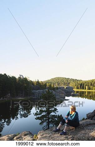 A Young Woman Sitting At The Water's Edge; Black Hills South Dakota United States Of America View Large Photo Image Stock Image - A Young Woman Sitting At The Water's Edge; Black Hills South Dakota United States Of America. Fotosearch
