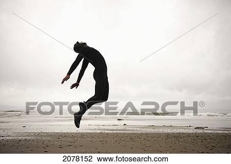 An individual wearing a wet suit jumping in mid-air on a beach; french beach british columbia canada View Large Photo Image Stock Image - An individual wearing a wet suit jumping in mid-air on a beach; french beach british columbia canada. Fotosearch
