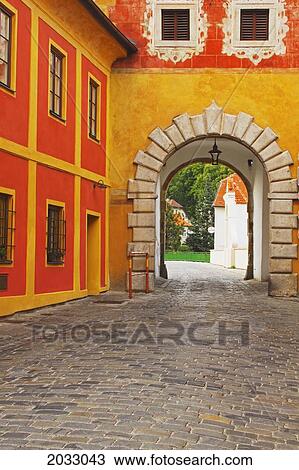 Stock Image - Arch And Cobblestone With An Orange And Yellow Building In Old Town; Cesky Krumlov Jihocesky Czech Republic. Fotosearch