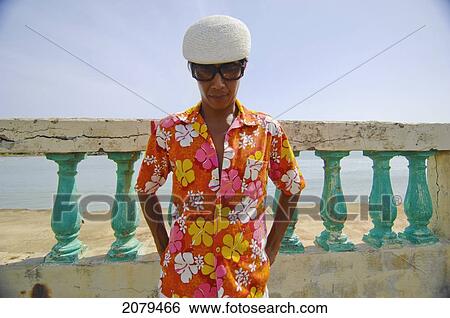 Asian man in bright flowered shirt in front of wall and ocean; puerto rico View Large Photo Image Stock Photograph - Asian man in bright flowered shirt in front of wall and ocean; puerto rico. Fotosearch
