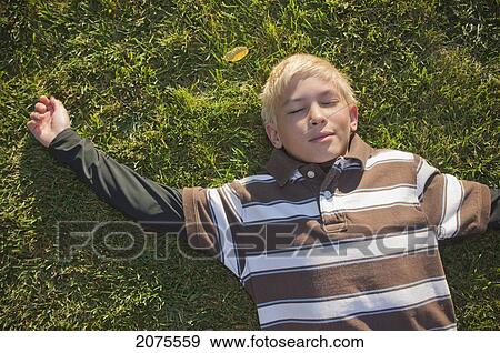 Stock Photo - Boy With Blond Hair Laying On The Grass; Moraga California United States Of America. Fotosearch