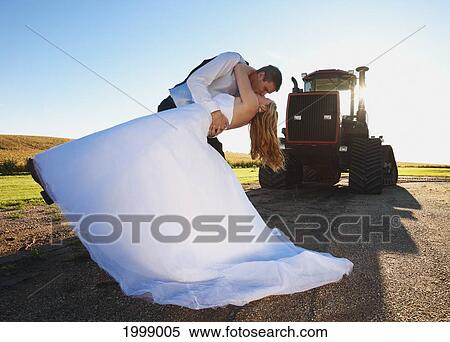 Bride And Groom Kissing In Front Of A Tractor; Pennock Minnesota United States Of America View Large Photo Image Stock Photography - Bride And Groom Kissing In Front Of A Tractor; Pennock Minnesota United States Of America. Fotosearch