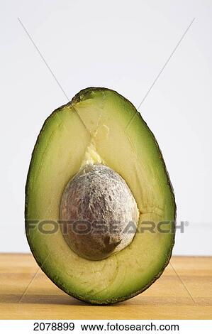 Close up of an avocado standing upright cut in half with the pit; calgary alberta canada View Large Photo Image Stock Photo - Close up of an avocado standing upright cut in half with the pit; calgary alberta canada. Fotosearch