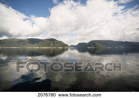 Stock Image - Clouds reflected in tranquil water; norway. Fotosearch