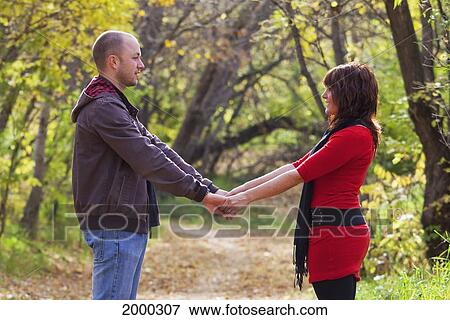 Couple Holding Hands On A Path In A Park; Edmonton Alberta Canada View Large Photo Image Stock Photo - Couple Holding Hands On A Path In A Park; Edmonton Alberta Canada. Fotosearch