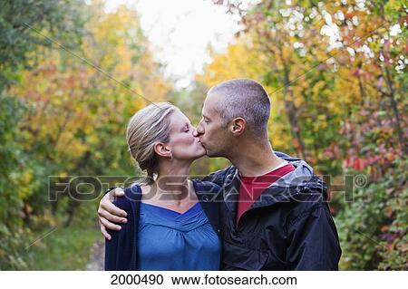 Stock Image - Couple Kissing While Walking Down A Park Path In Autumn; Edmonton Alberta Canada. Fotosearch