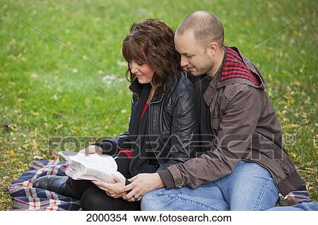 Couple Reading Bible Together In The Park; Edmonton Alberta Canada View Large Photo Image Picture - Couple Reading Bible Together In The Park; Edmonton Alberta Canada. Fotosearch
