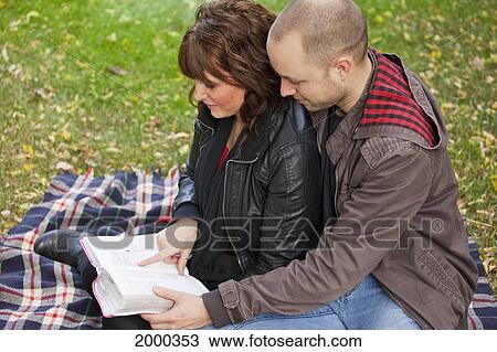 Stock Image - Couple Reading Bible Together In The Park; Edmonton Alberta Canada. Fotosearch