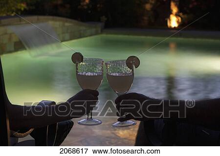 Couple Sitting At Pool Side At Night With Two Glasses Together With Lime Wedges And Pool Lights; Palm Springs California United States Of America View Large Photo Image Stock Photo - Couple Sitting At Pool Side At Night With Two Glasses Together With Lime Wedges And Pool Lights; Palm Springs California United States Of America. Fotosearch