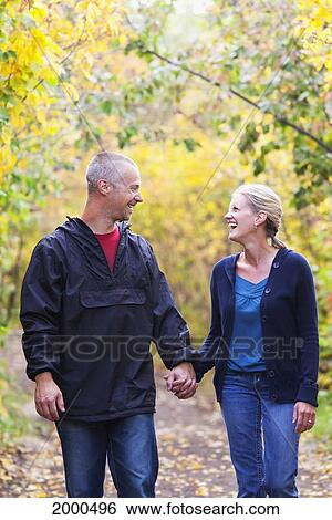 Stock Photograph - Couple Walking Together On A Park Path In Autumn; Edmonton Alberta Canada. Fotosearch