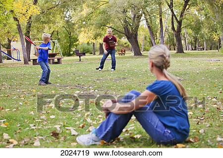 Stock Photo - Father And Son Playing Baseball In A Park With A Mother Watching; Edmonton Alberta Canada. Fotosearch