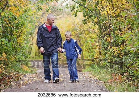 Stock Photograph - Father And Son Walking On A Path In A Park In Autumn; Edmonton Alberta Canada. Fotosearch
