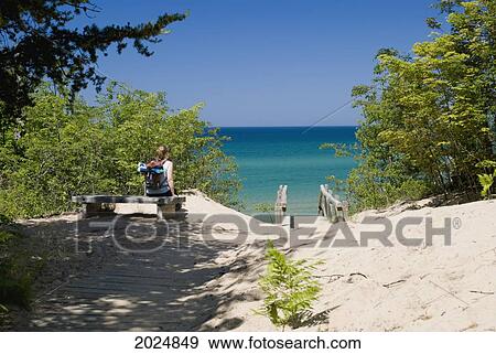 Stock Photo - Female On A Bench Looking At The Beach And The Water Of Lake Superior; Michigan United States Of America. Fotosearch
