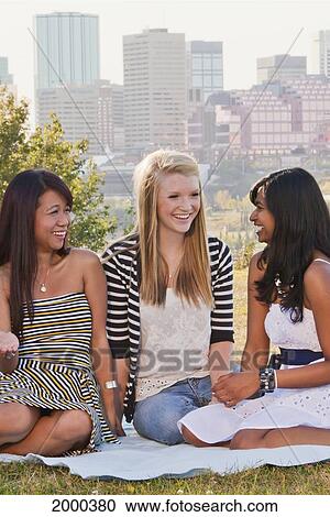 Stock Image - Friends Hanging Out In A City Park With The City Skyline In The Background; Edmonton Alberta Canada. Fotosearch
