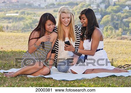 Stock Image - Friends Looking At A Smart Phone In A City Park; Edmonton Alberta Canada. Fotosearch
