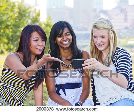 Stock Photo - Friends Looking At A Smart Phone With A City Skyline In The Background; Edmonton Alberta Canada. Fotosearch