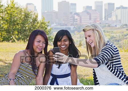 Friends Looking At A Smart Phone With A City Skyline In The Background; Edmonton Alberta Canada View Large Photo Image Stock Photograph - Friends Looking At A Smart Phone With A City Skyline In The Background; Edmonton Alberta Canada. Fotosearch