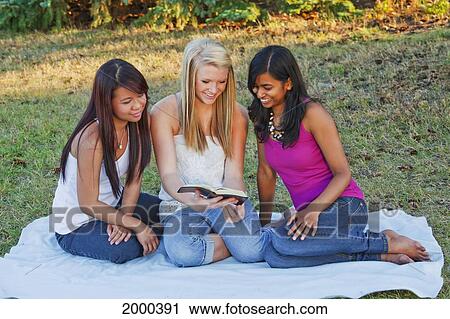 Stock Image - Friends Reading The Bible Together In A Park; Edmonton Alberta Canada. Fotosearch