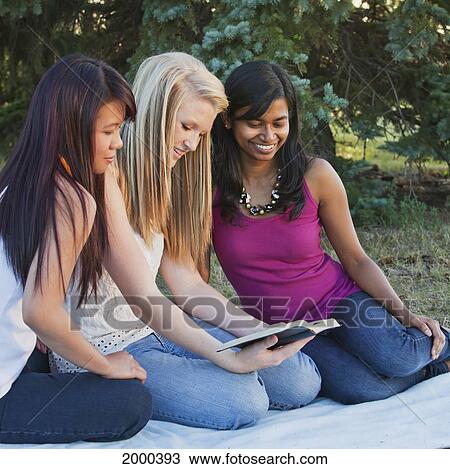 Stock Image - Friends Reading The Bible Together In A Park; Edmonton Alberta Canada. Fotosearch