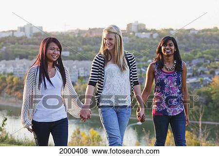 Stock Photo - Friends Walking In A City Park With The City Skyline In The Background; Edmonton Alberta Canada. Fotosearch