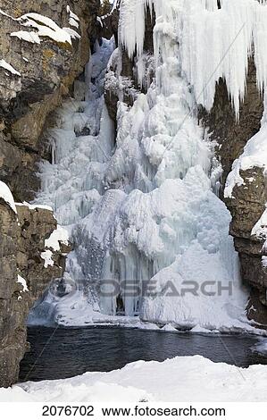 Stock Image - Frozen waterfalls with icicles snow covered cliff and open water; alberta canada. Fotosearch