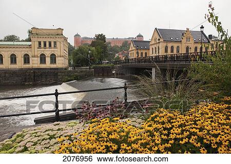 Stock Photograph - Fyris river and pump house with colourful flowers in the foreground; uppsala sweden. Fotosearch