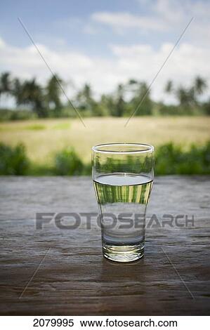 Glass of water on a table with rice fields in the background; bali indonesia View Large Photo Image Stock Photography - Glass of water on a table with rice fields in the background; bali indonesia. Fotosearch