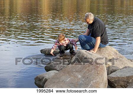 Grandfather And Grandson Playing Along The Rocks At The River's Edge; Edmonton Alberta Canada View Large Photo Image Picture - Grandfather And Grandson Playing Along The Rocks At The River's Edge; Edmonton Alberta Canada. Fotosearch