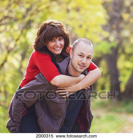 Husband Carrying His Wife Piggy Back In A Park In Autumn; Edmonton Alberta Canada View Large Photo Image Stock Photography - Husband Carrying His Wife Piggy Back In A Park In Autumn; Edmonton Alberta Canada. Fotosearch